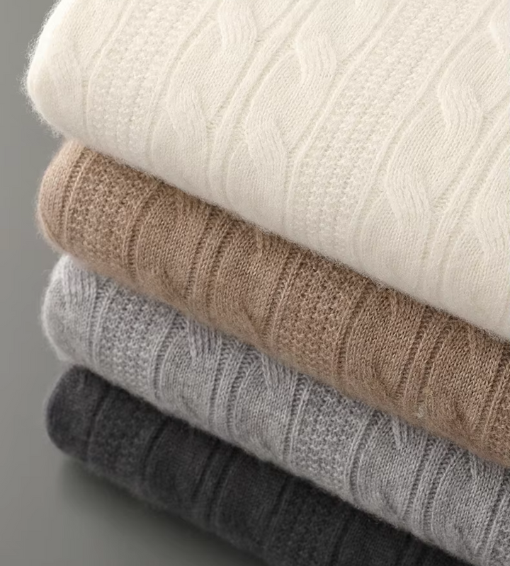 Stack of cable knit jumpers in off white, dark beige, light grey and dark grey