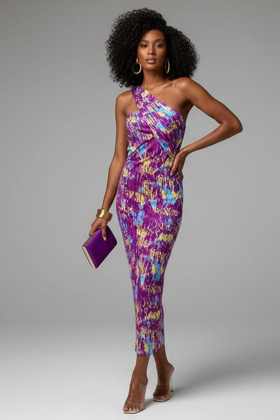 A woman wearing a colorful geometric patterned diagonal shoulder dress with a sleeveless design, paired with pink accessories.