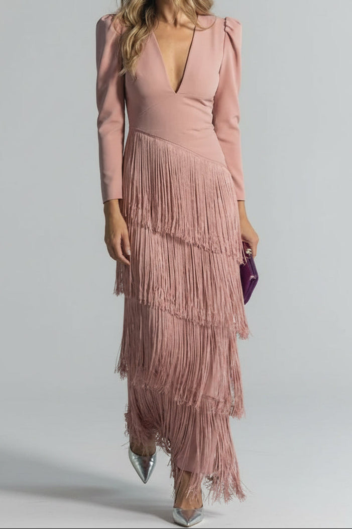 Woman wearing a pink dress with fringe details against a gray background