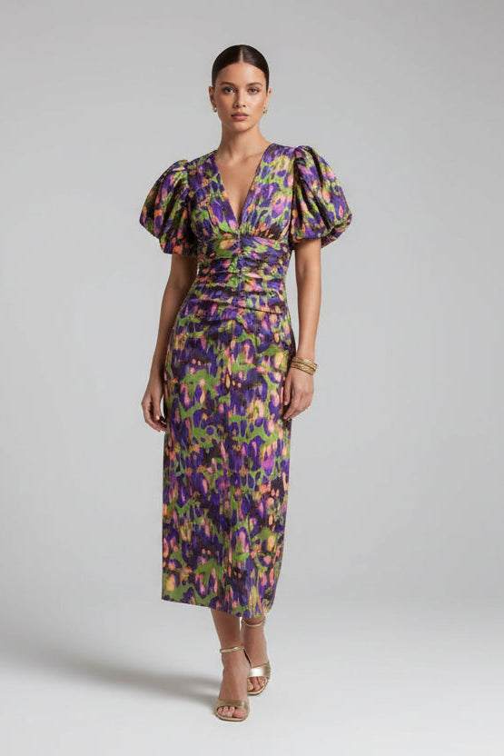 Woman in a floral dress walking outdoors near a building with columns.